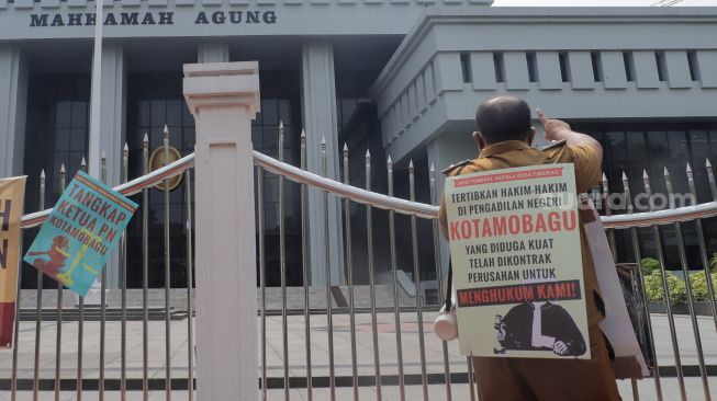 Kepala Desa Tiberias, Abner Patras saat menggelar aksi demo tunggal di depan Gedung Mahkamah Agung RI, Jakarta Pusat, Rabu (5/7/2023). [Suara.com/Alfian Winanto]