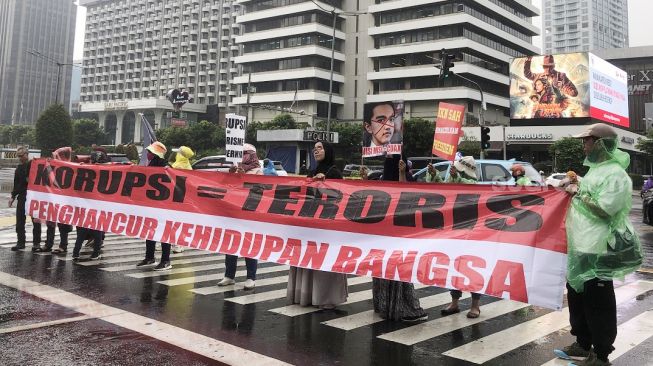 Puluhan emak-emak yang mengatasnamakan Aliansi Rakyat Menggugat membentangkan poster saat menggelar aksi kritik Presiden Jokowi di persimpangan Sarinah, Jalan MH Thamrin Jakarta Pusat, Jumat (7/7/2023). [Suara.com/Dea]