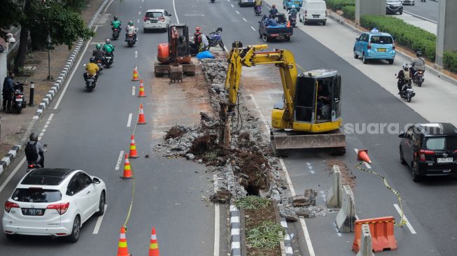Pekerja membongkar pembatas Jalan HR Rasuna Said di Kuningan, Jakarta, Jumat (7/7/2023). [Suara.com/Alfian Winanto]
