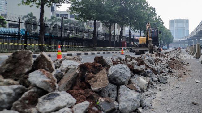 Pekerja membongkar pembatas Jalan HR Rasuna Said di Kuningan, Jakarta, Jumat (7/7/2023). [Suara.com/Alfian Winanto]
