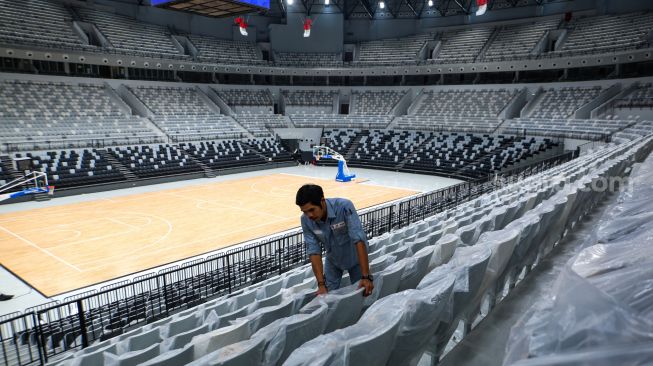 Petugas membersihkan tribun penonton di Indonesia Arena, Senayan, Jakarta, Selasa (11/7/2023). [Suara.com/Alfian Winanto]