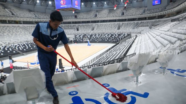 Petugas membersihkan tribun penonton di Indonesia Arena, Senayan, Jakarta, Selasa (11/7/2023). [Suara.com/Alfian Winanto]