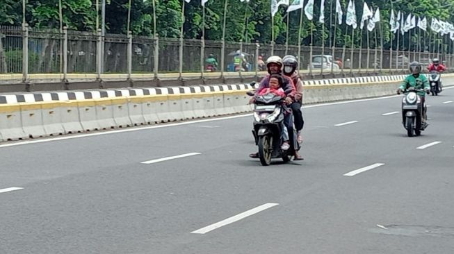 Salah satu bentuk keteledoran: orangtua mengenakan helm malahan anak tidak diberikan perlindungan sama sekali [PT WMS].