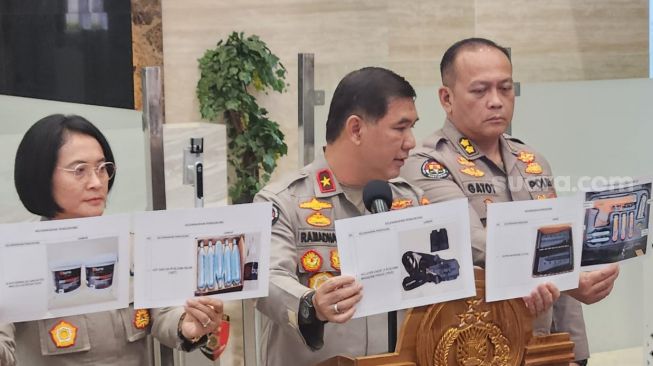 Karo Penmas Divisi Humas Polri Brigjen Ahmad Ramadhan melihatkan gambar pistol beramunisi bubuk lada dan gas air mata yang baru dibeli. (Suara.com/Rakha)