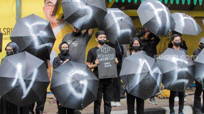 Sejumlah massa saat menggelar aksi unjuk rasa 'Payung Duka' di depan Kementerian Kesehatan, Jakarta, Jumat (14/7/2023). [Suara.com/Alfian Winanto]