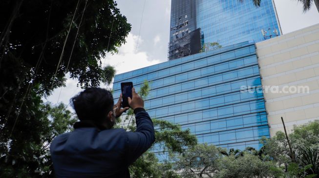 Warga merekam videotron yang terbakar di Menara K-Link, Jakarta, Sabtu (15/7/2023). [Suara.com/Alfian Winanto]