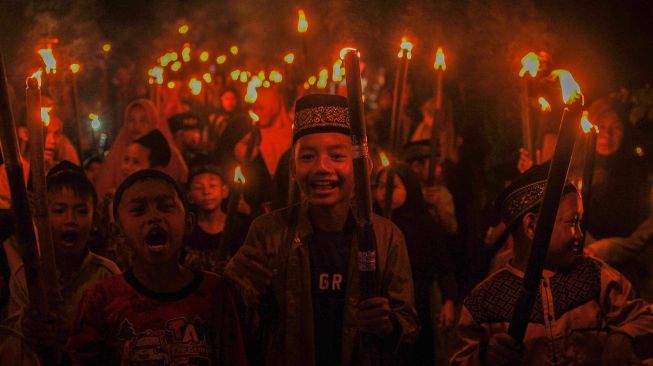 Sejumlah warga membawa obor saat mengikuti Pawai Tahun Baru Islam di Tunas Baru, Muaro Jambi, Jambi, Selasa (18/7/2023). [ANTARA FOTO/Wahdi Septiawan].