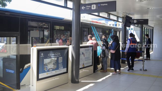 Calon penumpang menunggu kedatangan bus Transjakarta di Halte Transjakarta Kampung Melayu, Jakarta, Rabu (19/7/2023). [Suara.com/Alfian Winanto]