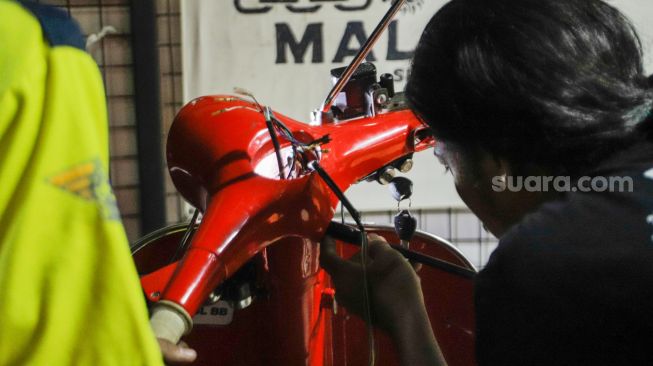 Pekerja mengkonversi vespa klasik menjadi vespa listrik di bengkel Elders Garage, Gedung Smesco Jakarta, Kamis (28/7/2022). [Suara.com/Alfian Winanto]