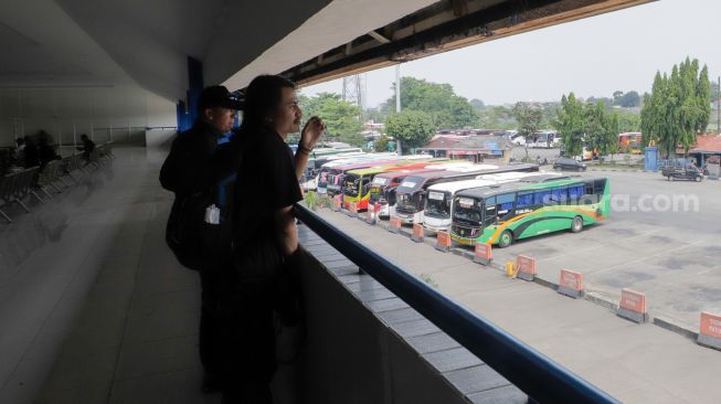 Sejumlah calon penumpang melihat bus dari loket lantai dua Terminal Kampung Rambutan, Jakarta Timur, Kamis (20/7/2023). [Suara.com/Alfian Winanto]
