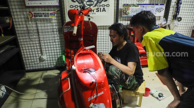 Pekerja mengkonversi vespa klasik menjadi vespa listrik di bengkel Elders Garage, Gedung Smesco Jakarta, Kamis (28/7/2022). [Suara.com/Alfian Winanto]