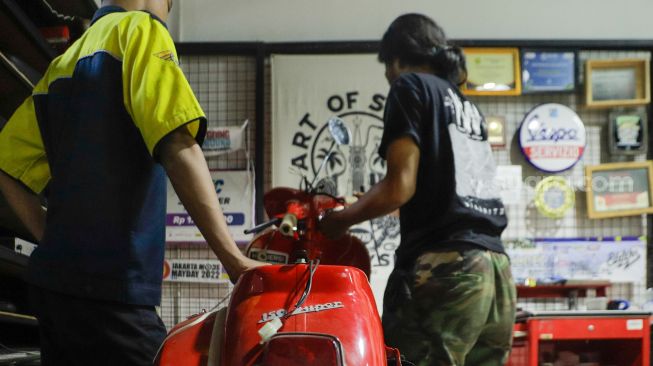 Pekerja mengkonversi vespa klasik menjadi vespa listrik di bengkel Elders Garage, Gedung Smesco Jakarta, Kamis (28/7/2022). [Suara.com/Alfian Winanto]