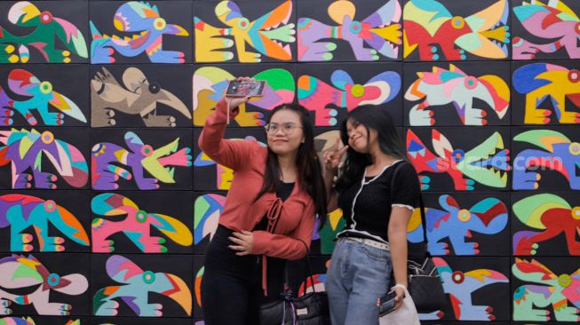 Pengunjung berswafoto di depan karya seni rupa karya Daniel Kho dalam pameran yang bertajuk Castaneda Factor di Galeri Jagad, Menteng, Jakarta, Minggu (23/7/2023). [Suara.com/Alfian Winanto]
