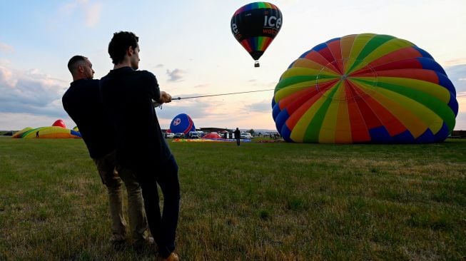 Peserta mempersiapkan balon udara untuk diterbangkan di pangkalan udara Chambley-Bussieres saat festival balon udara internasional ke-18 "Grand-Est Mondial Air Ballons" di Hageville, Prancis, Jumat (21/7/2023). [Jean-Christophe VERHAEGEN / AFP]