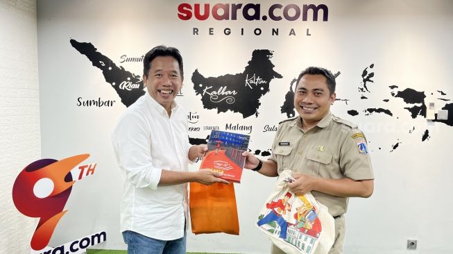 Kepala Bidang Komunikasi Publik Dinas Kominfotik DKI Jakarta, Koharudin memberikan buku tentang Jakarta ke Pemimpin Redaksi Suara.com Suwarjono usai media visit di Kantor Suara.com di kawasan Mega Kuningan, Jakarta Selatan. [Suara.com/Dwi Bowo Raharjo]