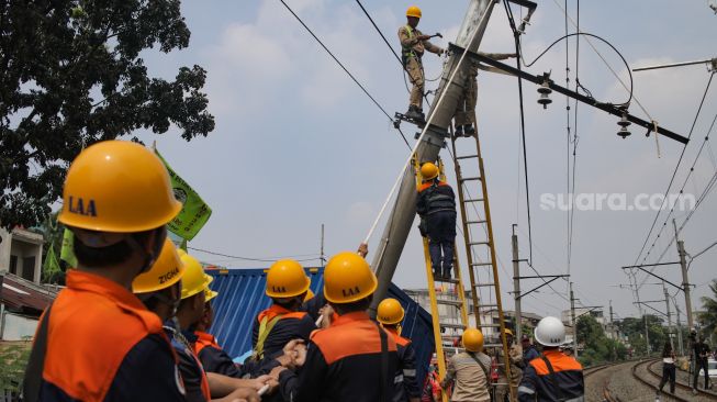 Petugas memutus aliran listrik pada tiang penyangga kabel KRL yang roboh di antara Perlintasan Pondok Ranji - Kebayoran, Jakarta, Selasa (25/7/2023). [Suara.com/Alfian Winanto]