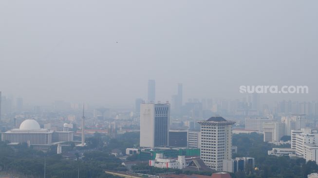 Suasana Ibukota yang mana terlihat samar lantaran polusi udara difoto dari menghadapi Gedung Perpustakaan Nasional (Perpusnas), Jakarta, Selasa (25/7/2023). [Suara.com/Alfian Winanto]
