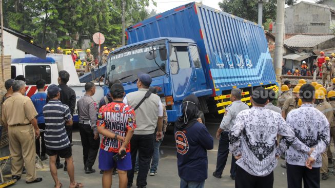 Petugas mengevakuasi truk yang menabrak tiang penyangga kabel KRL di antara Perlintasan Pondok Ranji - Kebayoran, Jakarta, Selasa (25/7/2023). [Suara.com/Alfian Winanto]