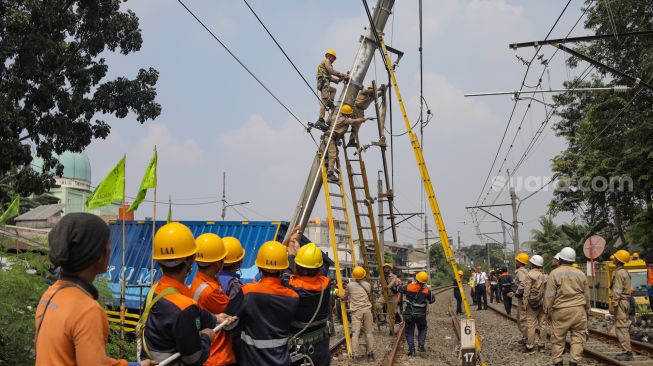 Petugas memutus aliran listrik pada tiang penyangga kabel KRL yang roboh di antara Perlintasan Pondok Ranji - Kebayoran, Jakarta, Selasa (25/7/2023). [Suara.com/Alfian Winanto]