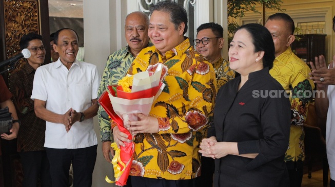 Ketua Umum Partai Golkar Airlangga Hartarto memberikan bunga kepada Ketua DPP PDIP Puan Maharani saat menggelar pertemuan di Kediaman Airlangga di Kebayoran Baru, Jakarta, Kamis (27/7/2023). [Suara.com/Alfian Winanto]