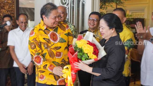 Ketua Umum Partai Golkar Airlangga Hartarto memberikan bunga kepada Ketua DPP PDIP Puan Maharani saat menggelar pertemuan di Kediaman Airlangga di Kebayoran Baru, Jakarta, Kamis (27/7/2023). [Suara.com/Alfian Winanto]