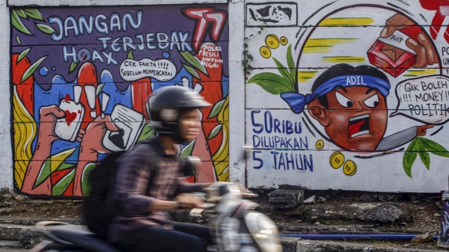 Pengendara melintas di depan mural bertemakan Pemilu di Jalan Raya Margonda, Depok, Jawa Barat, Jumat (28/7/2023). [ANTARA FOTO/Yulius Satria Wijaya].