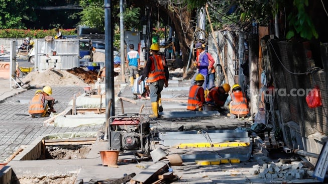 Pekerja saat menyelesaikan revitalisasi trotoar di kawasan Blok M, Jakarta Selatan, Selasa (1/8/2023).  [Suara.com/Alfian Winanto]