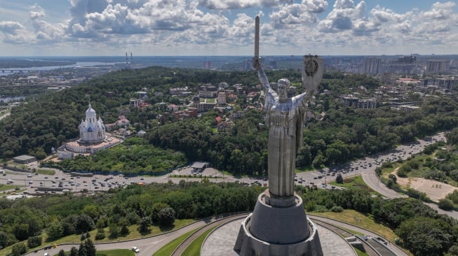 Gambar udara menunjukkan para pekerja sedang membongkar lambang bekas Uni Soviet dari perisai Monumen Ibu Pertiwi di Kyiv, Ukraina, Selasa (1/8/2023). [Sergii VOLSKYI/AFP]