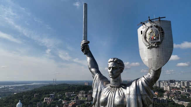 Gambar udara menunjukkan para pekerja sedang membongkar lambang bekas Uni Soviet dari perisai Monumen Ibu Pertiwi di Kyiv, Ukraina, Selasa (1/8/2023). [Sergii VOLSKYI/AFP]