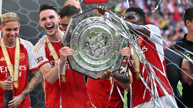 Gelandang Arsenal, Declan Rice (kedua kiri) mengangkat trofi Community Shield usai mengalahkan Manchester City lewat adu penalti dalam laga di Wembley Stadium, London, Inggris, Minggu (6/8) malam WIB. [Glyn KIRK / AFP]