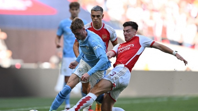 Pemain Manchester City, Cole Palmer (tengah) berduel dengan bek sayap Arsenal, Kieran Tierney pada laga Community Shield 2023 di Stadion Wembley, London, Inggris, Minggu (6/8) malam WIB. [JUSTIN TALLIS / AFP]