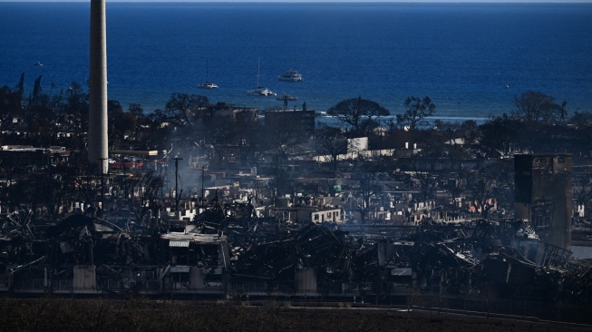 Sebuah cerobong asap berdiri di antara bangunan kota yang terbakar akibat kebakaran hutan hebat yang melanda di Lahaina, Maui barat, Hawaii, Jumat (11/8/2023). [Patrick T. Fallon / AFP]