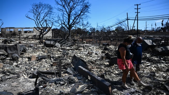 Warga mencari harta benda dari puing-puing rumah mereka setelah kebakaran hutan hebat yang melanda di Lahaina, Maui barat, Hawaii, Jumat (11/8/2023). [Patrick T. Fallon / AFP]