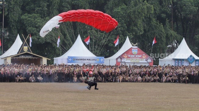 Atraksi terjun payung saat upacara pembukaan Raimuna Nasional (Rainas) XII di Bumi Perkemahan Cibubur, Jakarta, Senin (14/8/2023). [Suara.com/Alfian Winanto]