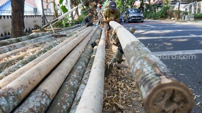 Pengrajin mengerjakan tahapan pembuatan batang  panjat pinang di kawasan, Manggarai, Jakarta, Senin (14/8/2023). [Suara.com/Alfian Winanto]