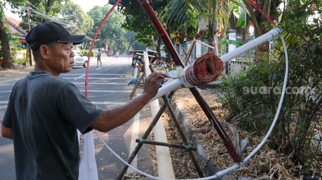 Pengrajin mengerjakan tahapan pembuatan batang  panjat pinang di kawasan, Manggarai, Jakarta, Senin (14/8/2023). [Suara.com/Alfian Winanto]