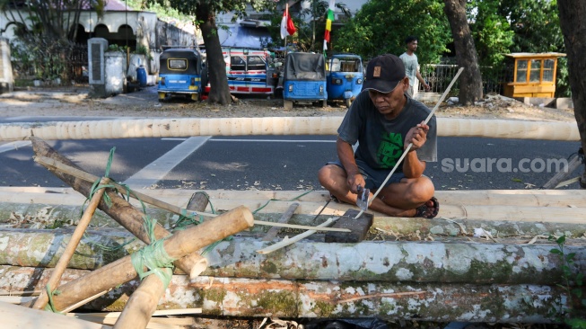 Pengrajin mengerjakan tahapan pembuatan batang  panjat pinang di kawasan, Manggarai, Jakarta, Senin (14/8/2023). [Suara.com/Alfian Winanto]