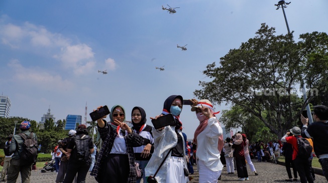 Warga berswafoto saat melihat atraksi udara di atas langit Jakarta, Kamis (17/8/2023). [Suara.com/Alfian Winanto]