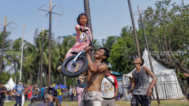 Peserta memamerkan hadiah lomba panjat pinang di Pantai Festival, Taman Impian Jaya Ancol, Jakarta, Selasa (17/8/2023). [Suara.com/Alfian Winanto]