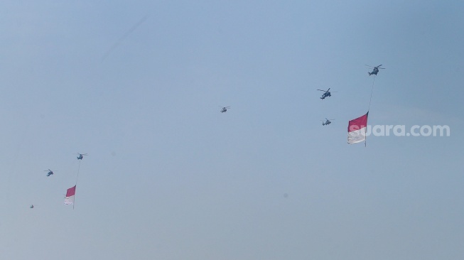 Helikopter membawa bendera merah putih melintas di Jakarta, Kamis (17/8/2023). [Suara.com/Alfian Winanto]