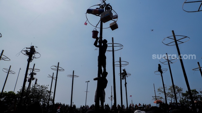 Peserta mengikuti lomba panjat pinang di Pantai Festival, Taman Impian Jaya Ancol, Jakarta, Selasa (17/8/2023). [Suara.com/Alfian Winanto]