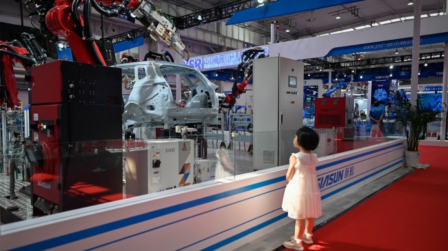 Seorang anak melihat lengan robot Siasun di Konferensi Robot Dunia 2023 di Beijing, China, Rabu (16/8/2023). [WANG Zhao / AFP]