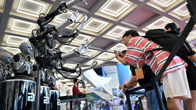 Pengunjung mengambil gambar lengan robot di Konferensi Robot Dunia 2023 di Beijing, China, Rabu (16/8/2023). [WANG Zhao / AFP]