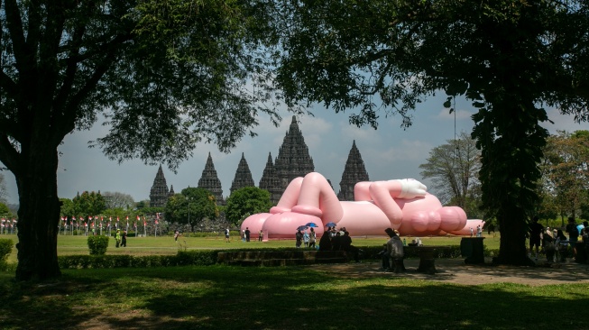 Pengunjung melihat instalasi seni dari yang dibuat oleh seniman dunia Brian Donnelly atau KAWS saat pameran bertajuk KAWS:HOLIDAY Indonesia di pelataran Candi Brahma di Kompleks Candi Prambanan, Sleman, Yogyakarta, Sabtu (19/8/2023).   [DEVI RAHMAN / AFP]