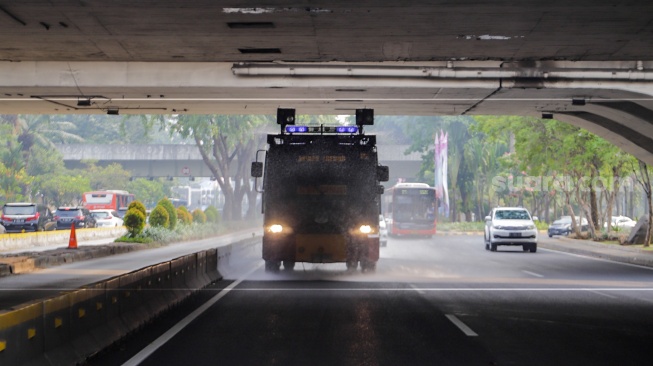 Mobil kepolisian melakukan penyiraman di kedua sisi di Jalan Jendral Sudirman hingga Patung Pemuda Membangun Senayan, Jakarta, Rabu (23/8/2023). [Suara.com/Alfian Winanto]