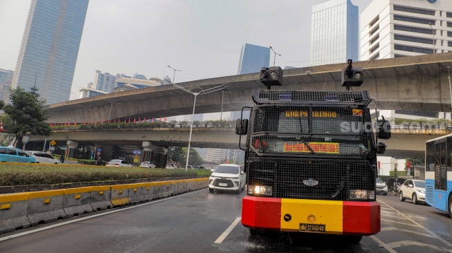 Mobil kepolisian melakukan penyiraman di kedua sisi di Jalan Jendral Sudirman hingga Patung Pemuda Membangun Senayan, Jakarta, Rabu (23/8/2023). [Suara.com/Alfian Winanto]