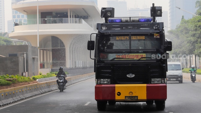 Mobil kepolisian melakukan penyiraman di kedua sisi di Jalan Jendral Sudirman hingga Patung Pemuda Membangun Senayan, Jakarta, Rabu (23/8/2023). [Suara.com/Alfian Winanto]