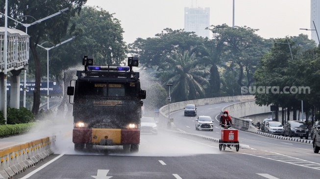 Mobil kepolisian melakukan penyiraman di kedua sisi di Jalan Jendral Sudirman hingga Patung Pemuda Membangun Senayan, Jakarta, Rabu (23/8/2023). [Suara.com/Alfian Winanto]