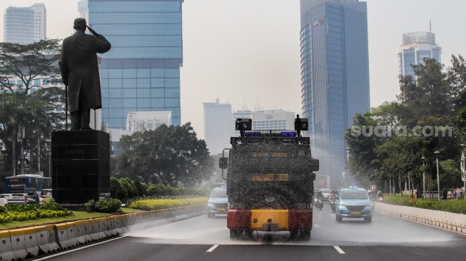 Mobil kepolisian melakukan penyiraman di kedua sisi di Jalan Jendral Sudirman hingga Patung Pemuda Membangun Senayan, Jakarta, Rabu (23/8/2023). [Suara.com/Alfian Winanto]