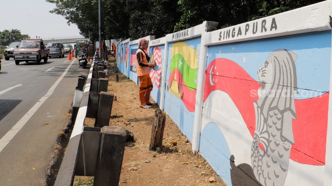 Petugas Penanganan Prasarana dan Sarana Umum (PPSU) membuat mural di Jalan Haji Bokir bin Djiun, Kramat Jati, Jakarta Timur, Kamis (24/8/2023). [Suara.com/Alfian Winanto]